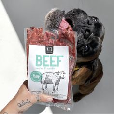 a dog is holding up a bag of beef for its owner to take it home