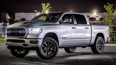 a white ram truck parked in a parking lot at night with its lights turned on