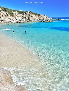 some people are swimming in the clear blue water on a sunny day at the beach