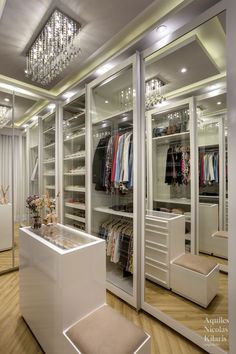 a walk in closet filled with lots of clothes and shoes next to a chandelier