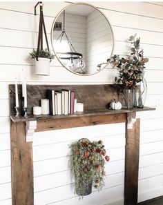 a fireplace mantel with books, candles and flowers on it in front of a mirror