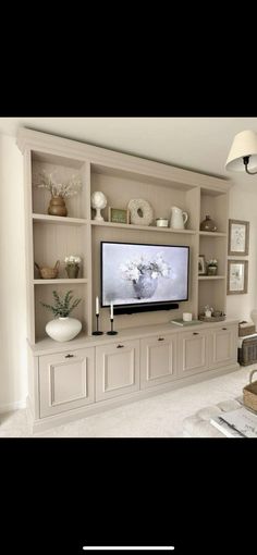 a living room with white furniture and a flat screen tv on the wall above it