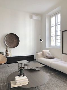 a living room filled with furniture and a large round mirror on the wall above it