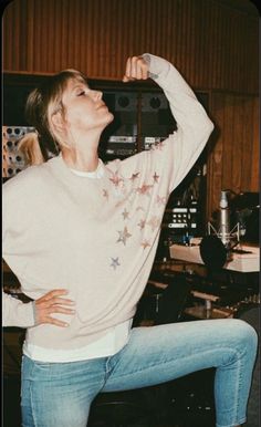 a woman standing on one leg with her arms behind her head in the air and looking up