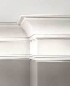 the corner of a room with white walls and molding on the ceiling is shown