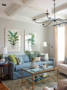 a living room with blue couches and green pillows on top of the sofas