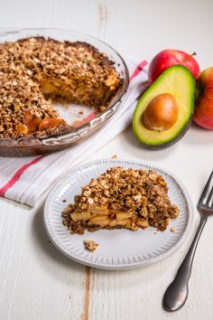 a piece of pie on a plate next to an avocado