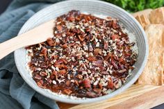 a bowl filled with food sitting on top of a cutting board next to crackers