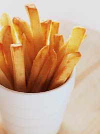 a white cup filled with french fries on top of a table