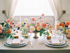 the table is set with silverware, plates and flowers in vases on it