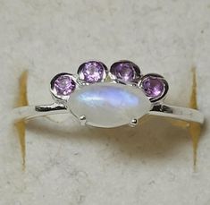 This is a sterling silver ring with rainbow moonstone or spectrolite and amethyst. The front of the ring is 3/8 of an inch wide by 1/4 of an inch tall.  This is a new, unworn, vintage store stock ring. It comes in a jewelry box for gifting. Purple Moonstone Gemstone Ring For Anniversary, Purple Moonstone Ring For Anniversary, Earrings Studs, Vintage Store, Rainbow Moonstone, New Vintage, Jewelry Earrings Studs, Sterling Silver Ring, Moonstone