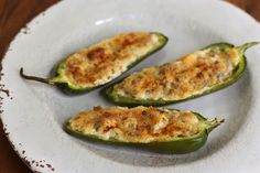 three stuffed green peppers on a white plate