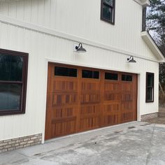 two garage doors are open in front of a white building with brown trim and windows