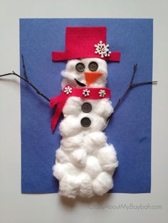 a snowman made out of yarn and buttons on a piece of paper with blue background