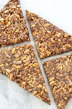 four pieces of granola and nuts arranged in the shape of a triangle on a white surface