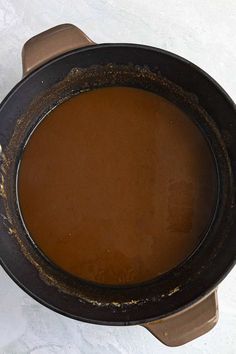 a pot filled with brown liquid sitting on top of a white tablecloth covered floor