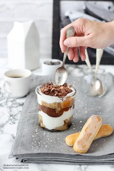 a person spoons into a dessert in a glass jar on top of a gray napkin