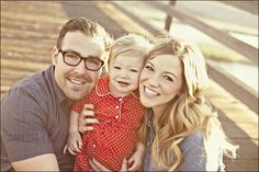 a man, woman and child are posing for a photo on the boardwalk with their arms around each other