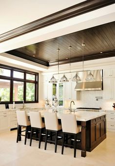 a large kitchen with white cabinets and marble counter tops, an island in the middle