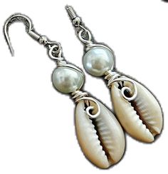 two seashells with pearls are hanging from silver earwires on a white background