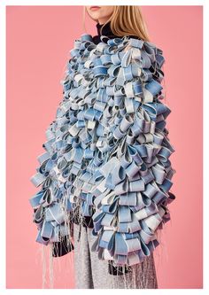 a woman wearing a large blue scarf made out of folded book pages with fringes