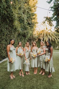 a group of women standing next to each other on top of a lush green field