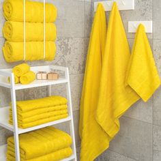 a bathroom with yellow towels hanging on the wall and shelving unit in front of it