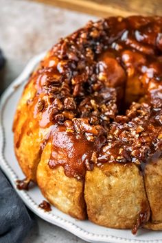 a bundt cake on a plate with pecans and caramel drizzle