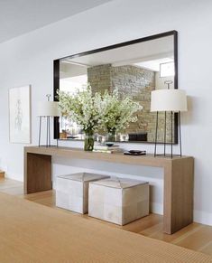 a living room with white walls and wooden flooring, a large mirror on the wall