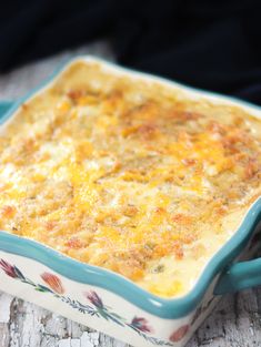 a casserole dish with cheese on it sitting on top of a wooden table