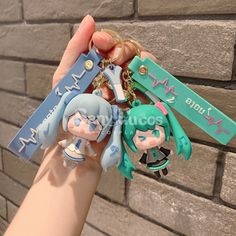 someone is holding two key chains in their hand, one has an anime character on it