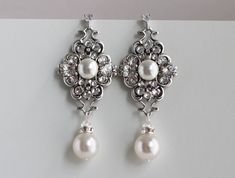 "These elegant earrings have antique silver filigrees decorated with premium Austrian crystals by hand and pearls in your choice of color.  Drop pearl measures 10 mm. Earrings measure approximately 2 1/2\" long from top to bottom. They have a cubic zirconia post.  Filigree has different sizes of  crystals.  Filigree measures just under 1 1/2\" by 7/8\" wide.  Glamorous for any bride! **If your dress is ivory I recommend the white color in my opinion it is an off white and works with white and ivory gowns.  The cream works with cream, light cream and some champagne shades.  If you need help deciding the color pearl that works best for you.  Please send me a picture of your dress and I am happy to help** Coordinating necklace, https://www.etsy.com/listing/124297852/pearl-necklacebridal-neckl Pearl Drop Earrings Wedding, Earrings For Bride, Drop Earrings Wedding, Bridal Earrings Chandelier, Wedding Chandelier, Crystal Bridal Earrings, Crystal Chandelier Earrings, Pearl Earrings Wedding, Bridal Earrings Pearl