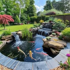 an outdoor pond surrounded by rocks and water features two goldfish swimming in the center