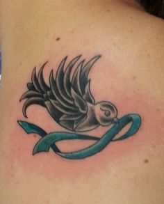 a bird tattoo on the back of a woman's shoulder, with an arrow