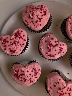 cupcakes with pink frosting in the shape of hearts on a white plate