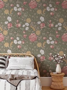 a bed sitting next to a wall with flowers on the wall and two vases