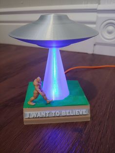 a small toy is sitting on top of a book with an alien lamp in the middle