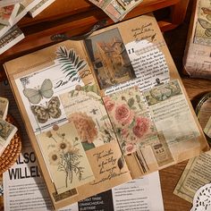 an open book sitting on top of a wooden table covered in lots of papers and pictures