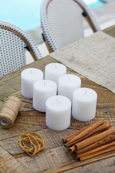 white candles and cinnamon sticks on a wooden table