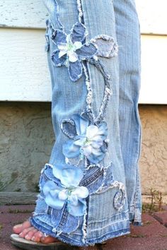 a pair of jeans with flowers on them and frayed off the bottom are standing in front of a door