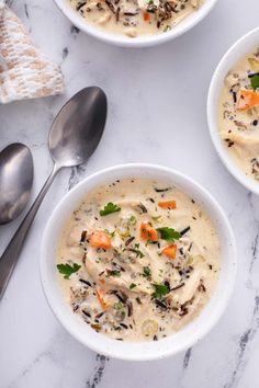 three bowls filled with soup on top of a white counter next to silver spoons