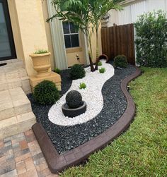 a small garden with rocks and plants in the front yard, next to a house