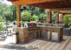 an outdoor kitchen with grill and seating area