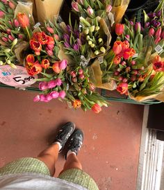 a person standing in front of a bunch of flowers with their feet on the ground