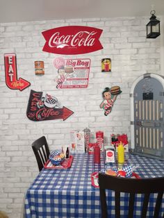 there is a table and chairs in the room with coca - cola signs on the wall