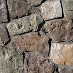 a stone wall that is made out of various types of rocks and has different colors