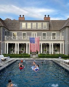 people are playing in the swimming pool with an american flag hanging from the building's roof