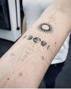 a woman's arm with the sun and planets on it, in front of a microwave