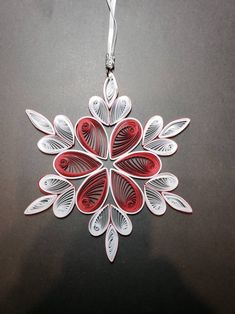 a red and white ornament hanging from a silver chain on a black surface