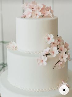 a white wedding cake with pink flowers on top